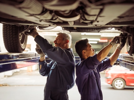 Two mechanics working underneath a car